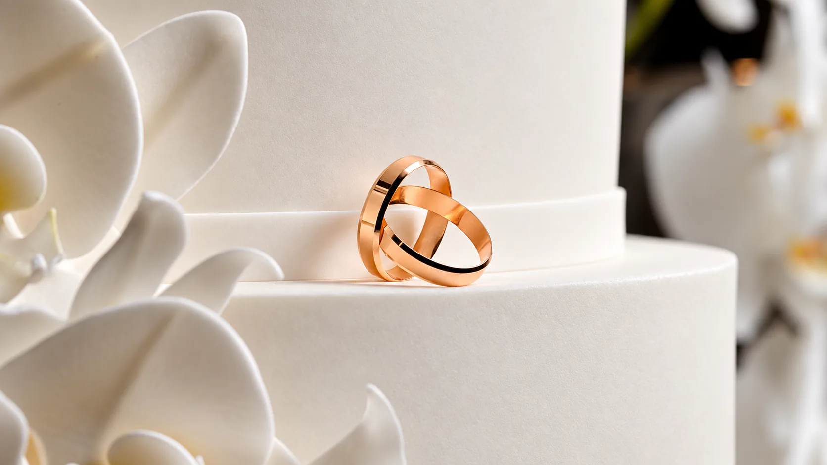 Alianças em ouro rosé sobre um bolo de casamento
